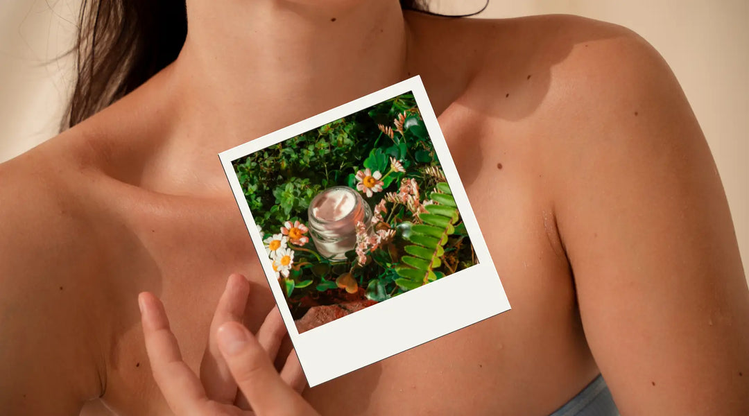 Close-up of a woman's chest holding a photo of a jar of natural skincare cream surrounded by flowers and greenery, highlighting organic skincare products.