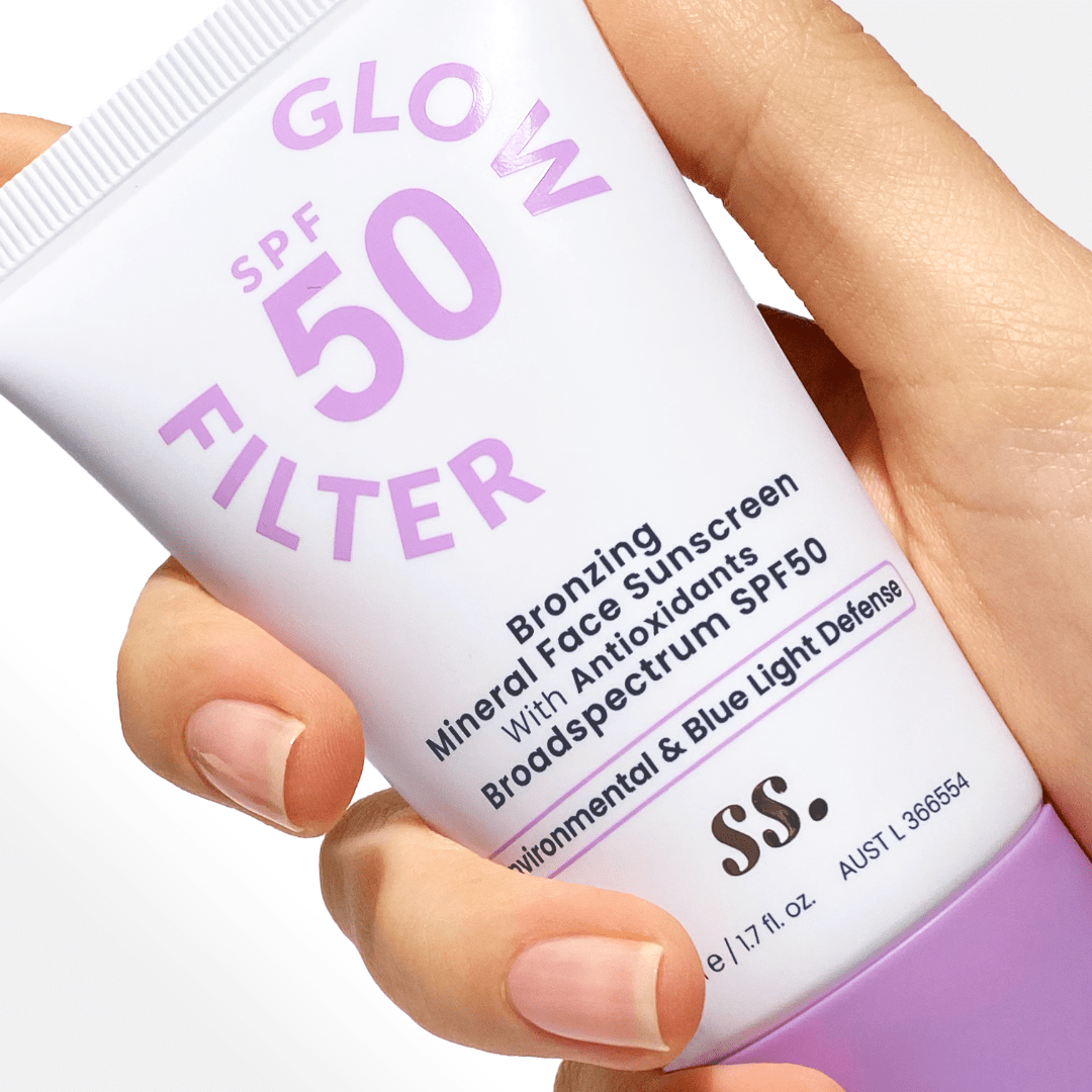 Close-up of a hand holding SS SPF 50 Glow Filter Bronzing Mineral Sunscreen with Antioxidants.