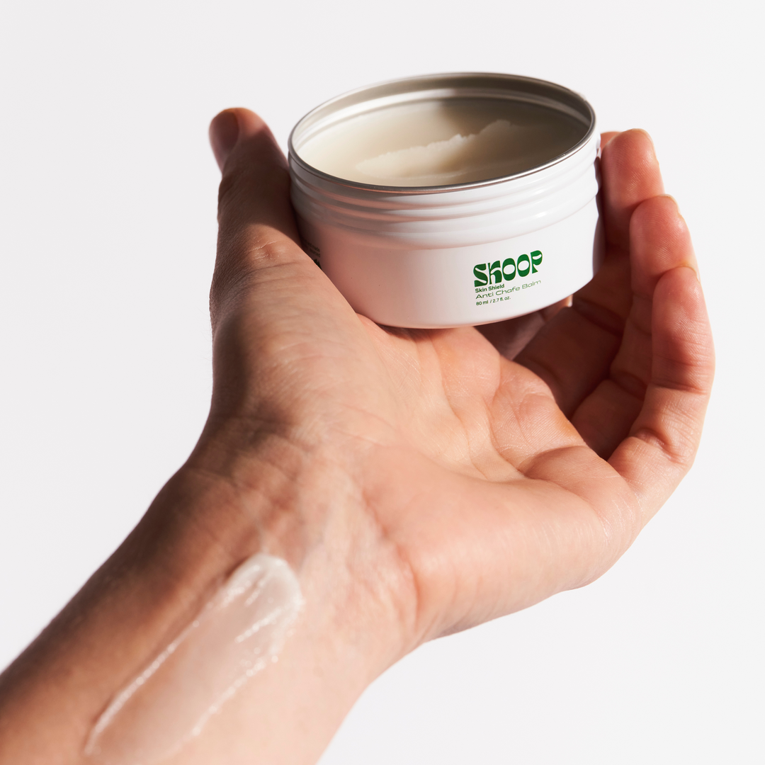 Skoop Skincare, Skin Shield, Anti Chafe Balm. Skoop Skincare tin being held by hand. Skoop Skincare logo visible. Anti Chafe Balm applied to wrist.