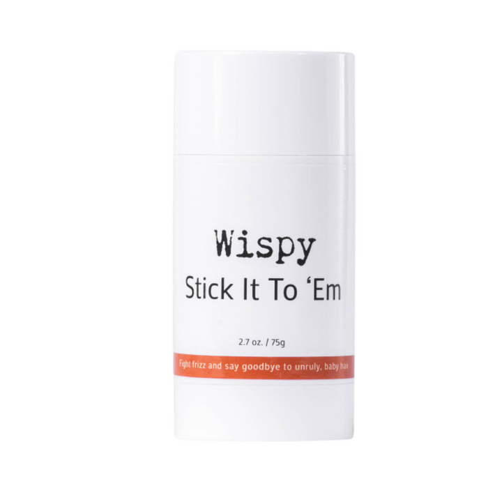 The image displays a white cylindrical container for a hair styling product named "Wispy Stick It To 'Em." It has a net weight of 2.7 oz or 75g. The label on the container features a playful and direct message, "fight frizz and say goodbye to unruly, baby hair," the product is used for smoothing and controlling frizzy hair and flyaways. This is a hair wax stick.