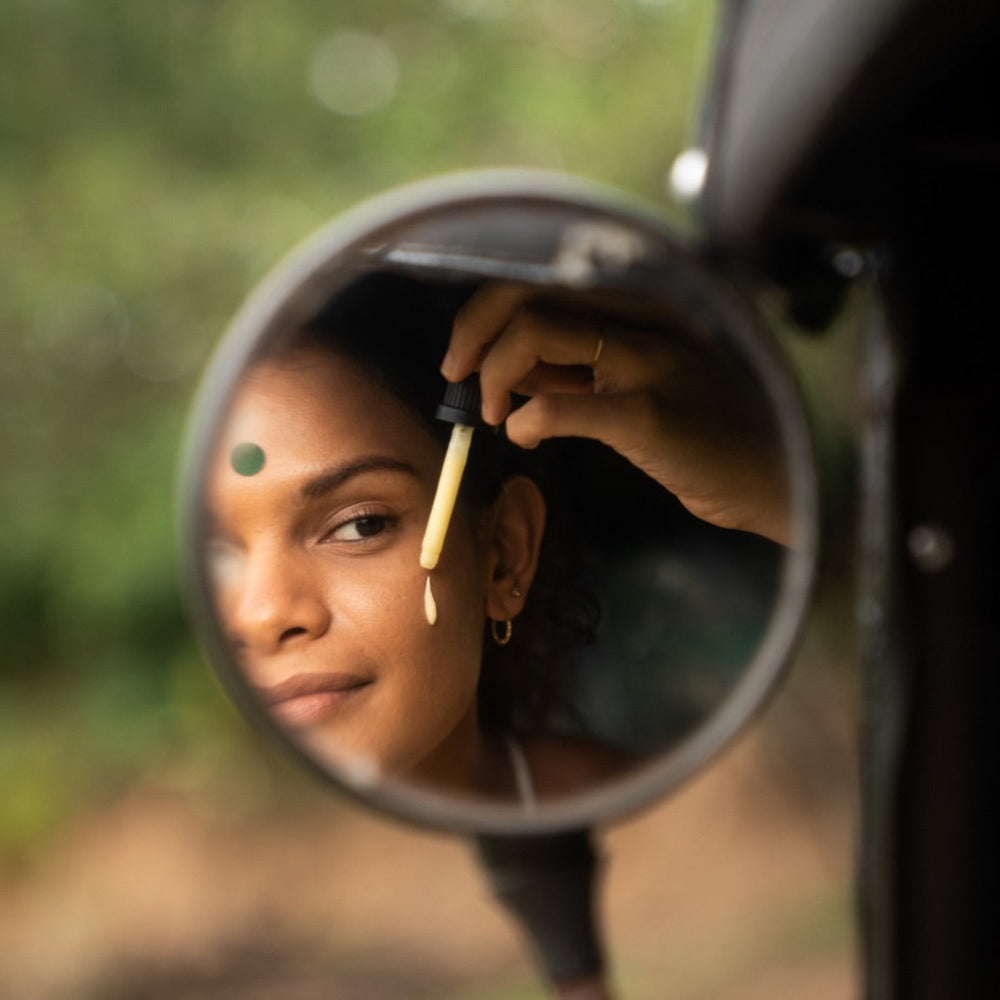 Close-up of a woman applying Bakuchiol Retinol with Kojic Acid skincare serum, reflected in a mirror, highlighting natural beauty and self-care.