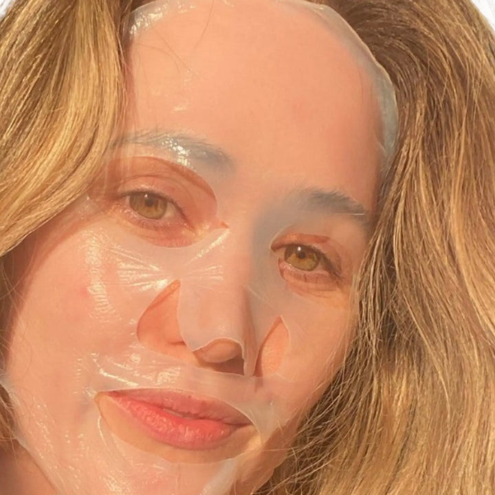 Woman with a bio-cellulose sheet mask on her face, sunlit room with blinds casting shadows, enjoying a self-care moment in Australia. Shop at VAMS beauty Biodegradable Bio Cellulose masks.
