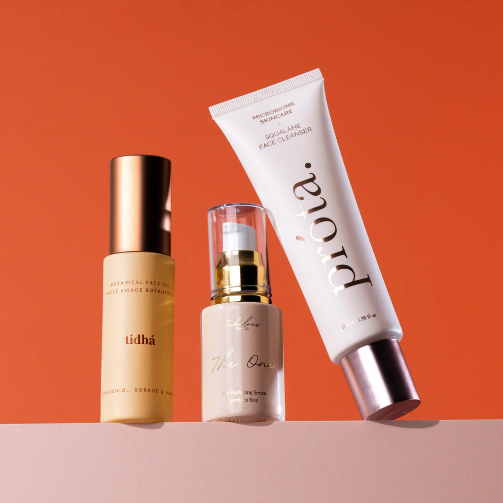 Three Australian skincare products displayed against an orange background, including Tidha Botanical Face Oil, The One Skin Perfecting Serum, and Prota Squalane Face Cleanser.