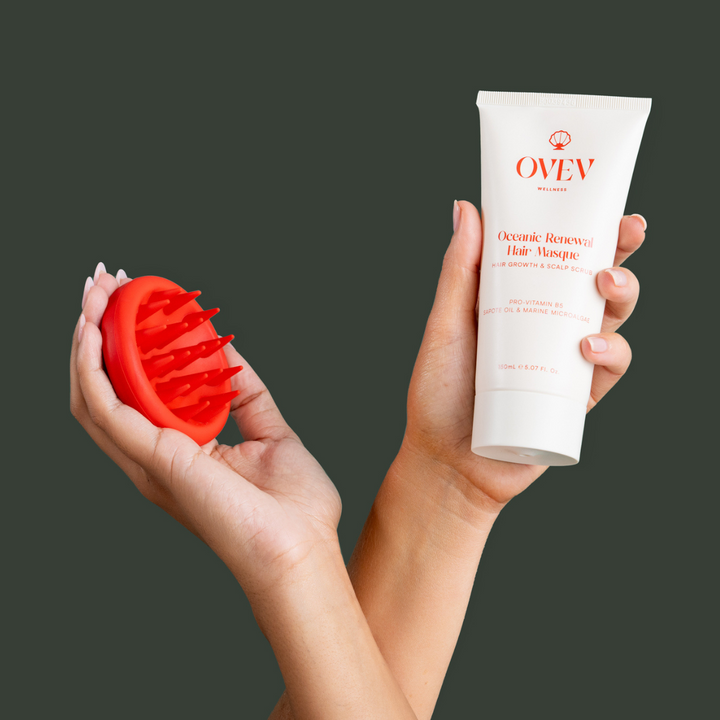 Hands holding OVEV Wellness Oceanic Renewal Hair Masque and red scalp scrubber, promoting hair growth and scalp care with Pro-Vitamin B5, Sapote Oil, and Marine Microalgae