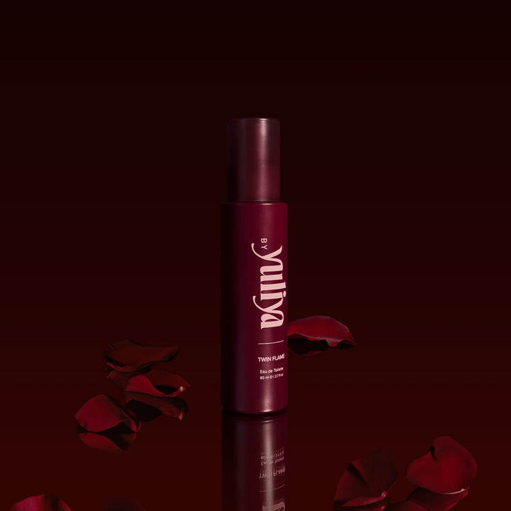 By Yuliya Twin Flame 80ml Perfume Mist, a deep and sensual fragrance with rich, romantic notes, set against a moody red backdrop with scattered rose petals, perfect for an alluring and long-lasting scent.