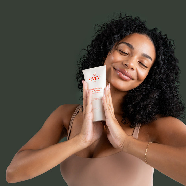 Smiling woman with curly hair holding OVEV Wellness Oceanic Renewal Hair Masque, promoting hair growth and scalp care with Pro-Vitamin B5, Sapote Oil, and Marine Microalgae