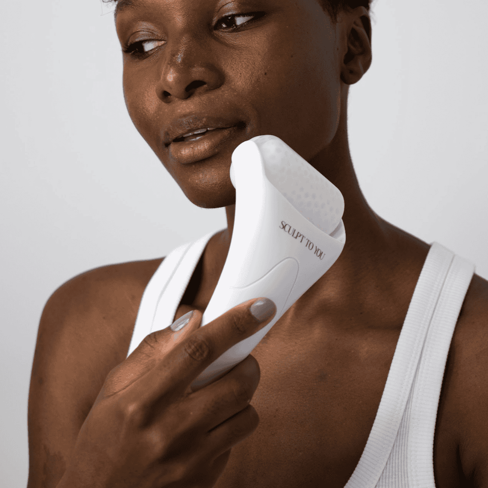 Model using Sculpt to You Face Ice Roller, available at VAMS Beauty. This white ice roller helps to soothe and refresh skin, reduce puffiness, and improve circulation, providing a cooling treatment for a rejuvenated complexion.