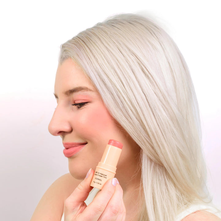 Model applying Avocado Zinc SPF 50 Natural Lip & Cheek Tint in Coral from VAMS Beauty. This Australian-made tint offers broad-spectrum sun protection and adds a natural, rosy color to lips and cheeks, perfect for enhancing your beauty routine with a moisturizing formula.