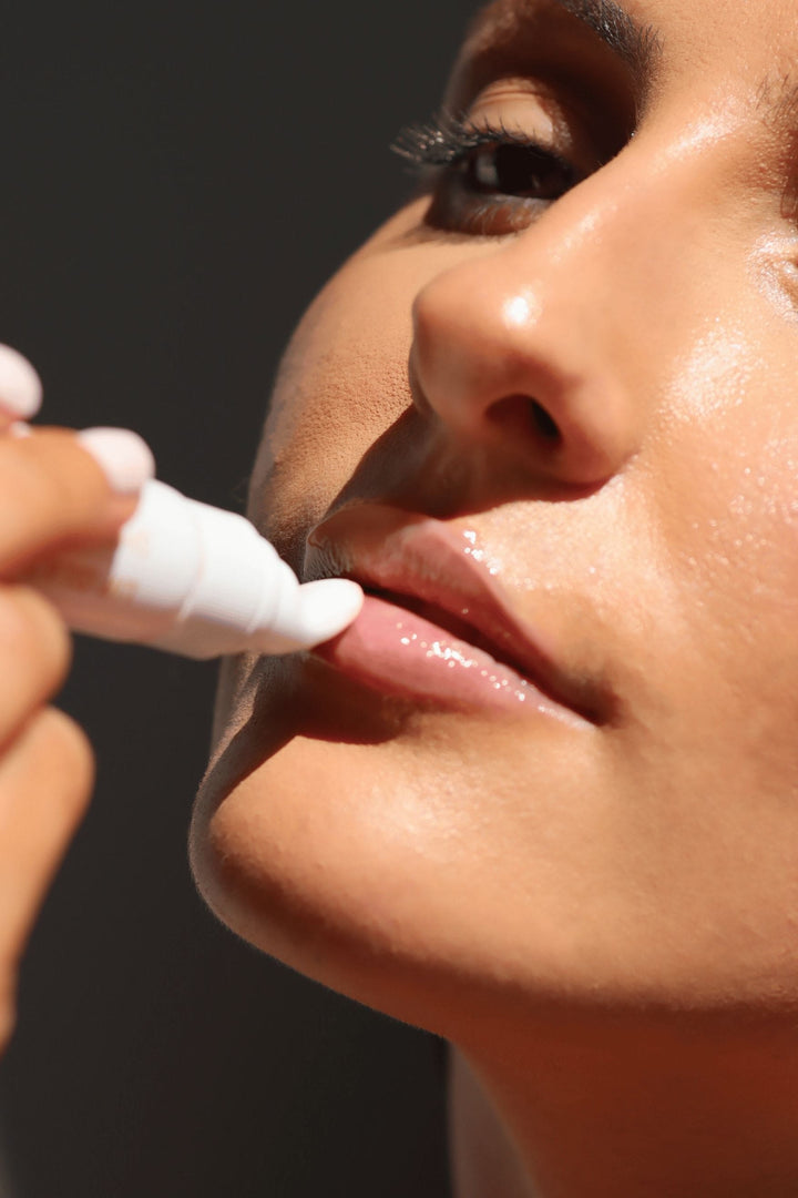 Close-up of woman applying Vani-T Lip Glaze Sheer Gloss for a natural, glossy finish and fuller-looking lips.